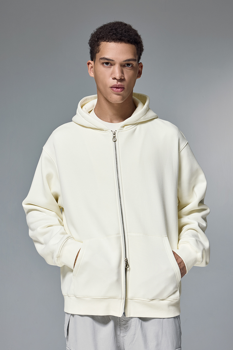 Person wearing a cream-colored hoodie against a gray background
