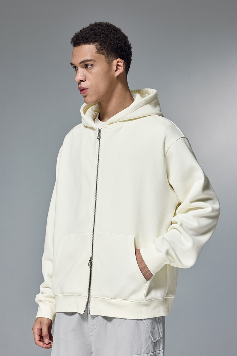 Person wearing a cream hoodie against a gray background